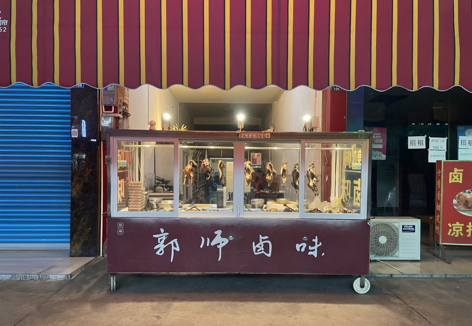 궈스루웨이 매장 외관: 빨강·노랑 차양 아래 신선 조림 오리가 걸리고, 수레에 궈스루웨이 글씨